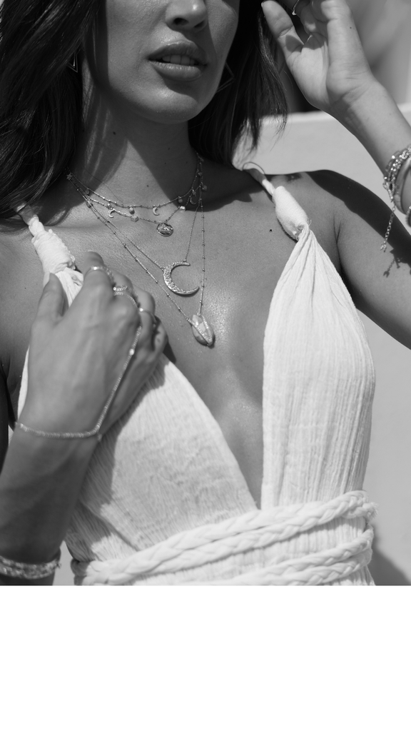 Black and white close-up of a person wearing a strapless top and layered necklaces.